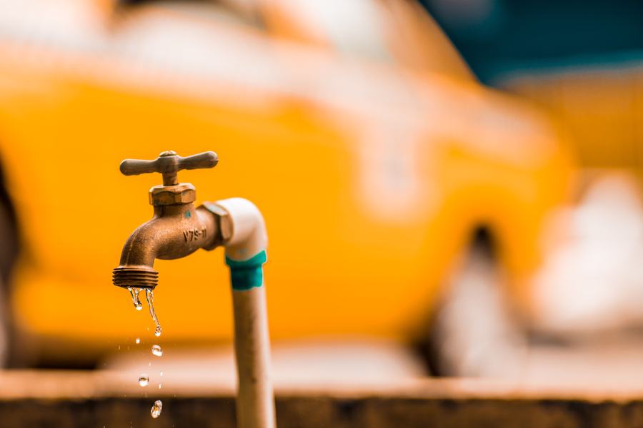 Robinet en laiton avec des gouttes d'eau en suspension, sur un fond flou